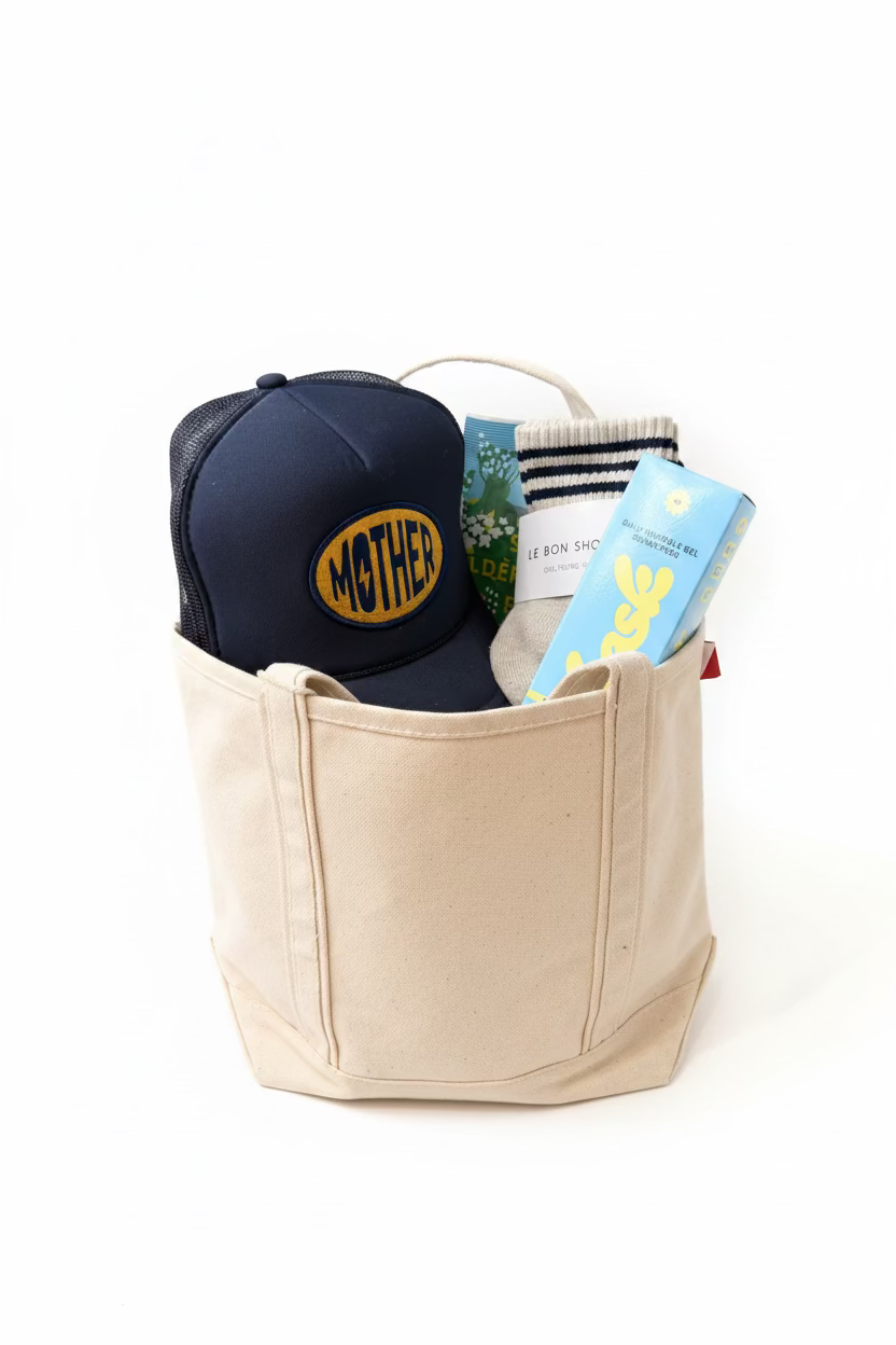 Beige bag with a navy cap labeled 'MOTHER', sunscreen, socks and candy