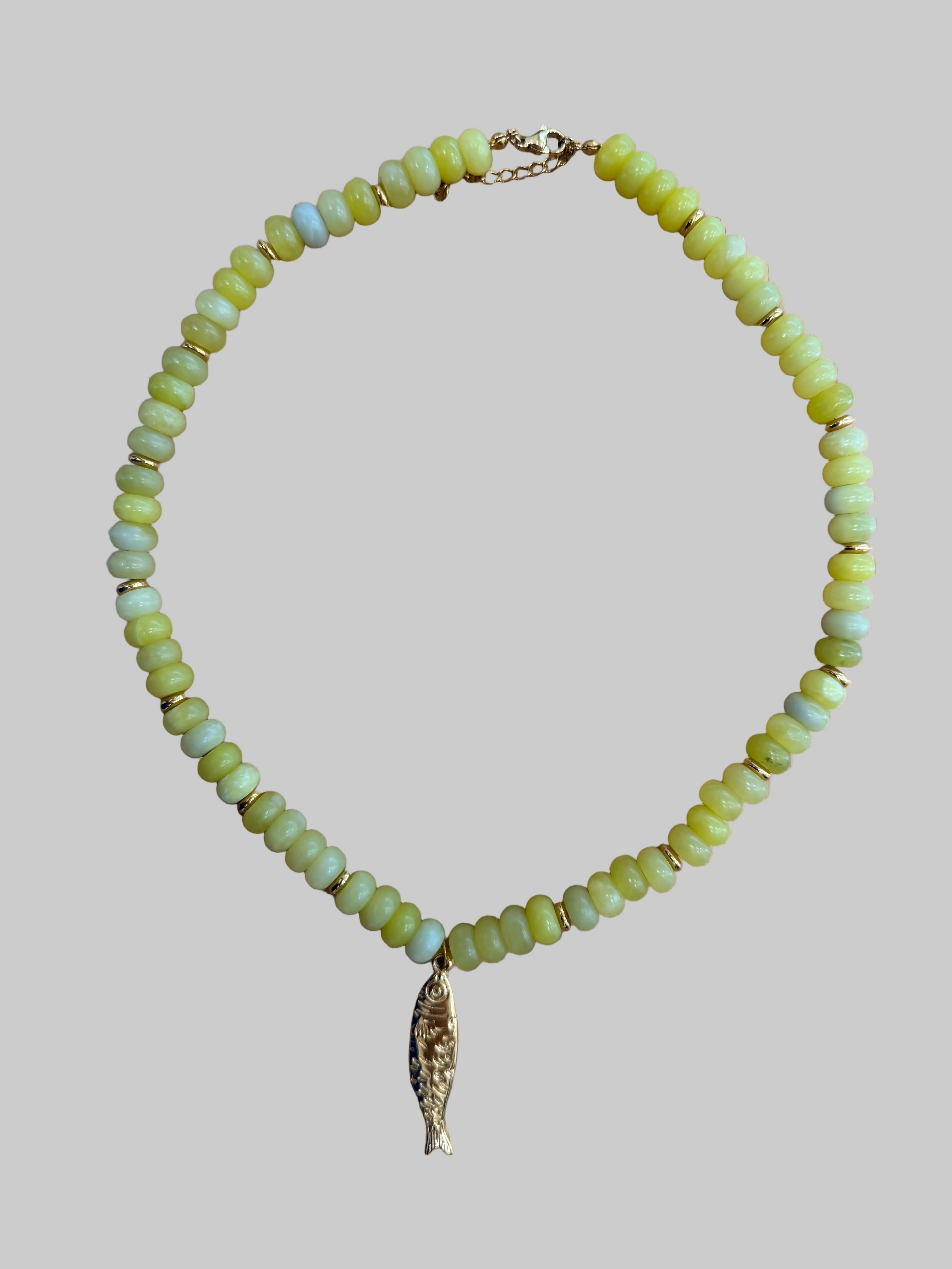 Necklace with green beads and a gold fish pendant